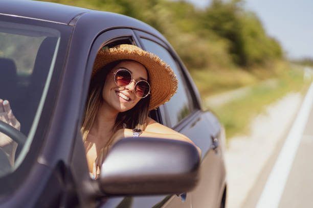 istock Smiling woman sitting in car and looking through window 1295860502