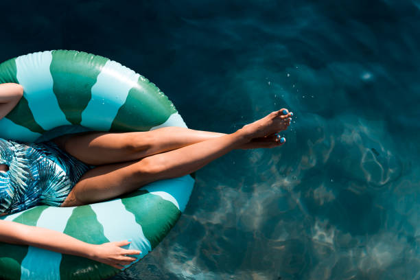 schöne frauen entspannen im pool, während sie auf aufblasbaren ring sitzen - swimming pool women floating on water bikini stock-fotos und bilder