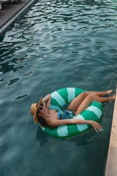 istock Beautiful women relaxing in the pool while sitting on inflatable ring 1295860577