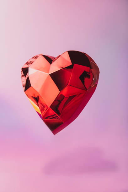 istock Sparkling levitating geometric heart with shadow on a neon pink background. Red polygonal heart for Valentine's day card. Love concept. Festive vertical background with copy space. Minimalism style. 1295862744