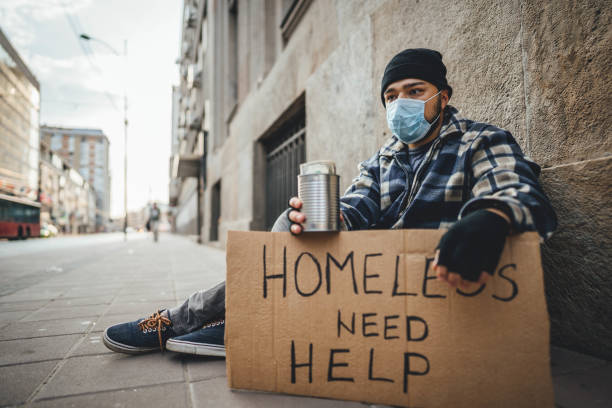 istock Homeless man sitting and asking for help while holding cardboard 1295862763