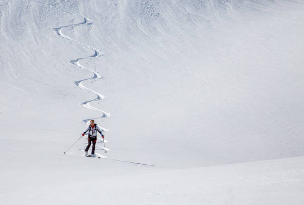 Backcountry skier descends snow slope in mountains