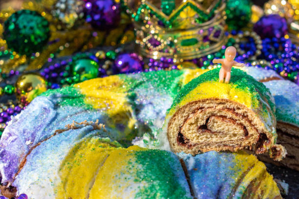 torta king del martedì grasso affettata condita con bambino giocattolo - mardi gras new orleans mask bead foto e immagini stock