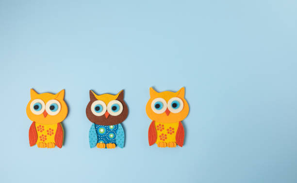 istock Three little owls isolated on blue background 1295867670