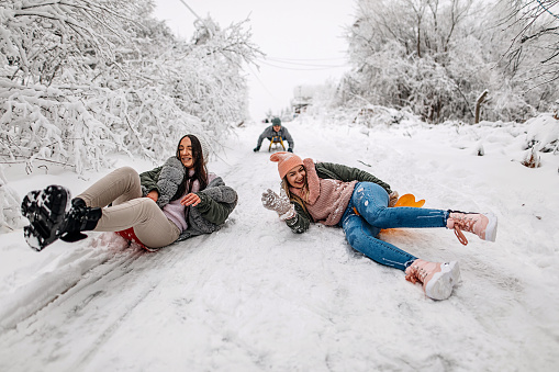 Friends are sledding in the snow