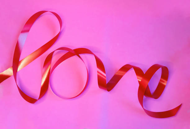 слово любовь написана с подарочной лентой на розовом фоне - picture of the word love стоковые фото и изображения