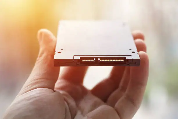 solid state disk drive or SSD close up. person holding data storage device computer hardware.