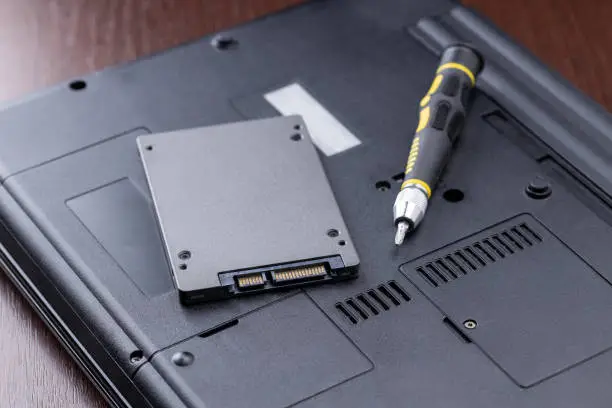 laptop repair service concept. man repairing or upgrading laptop hardware. person using screwdriver to open broken laptop.