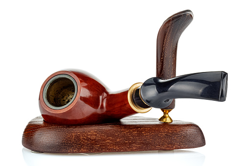 Used empty smoking tobacco pipe lying on side in wooden holder isolated on white background close-up