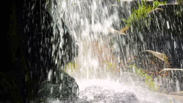 The waterfall is pouring,a beautiful stream of water,splashes and beautiful drops in a natural waterfall.
