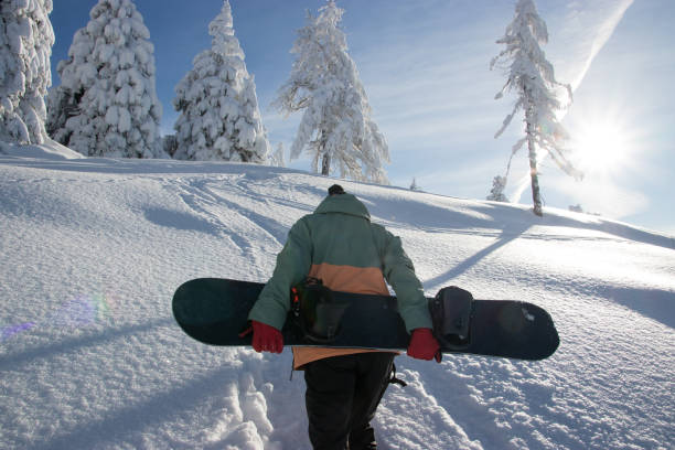istock Snowboarder carrying a snowboard 1295871088