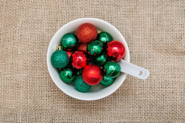 Red and green Christmas baubles in white bowl with spoon.