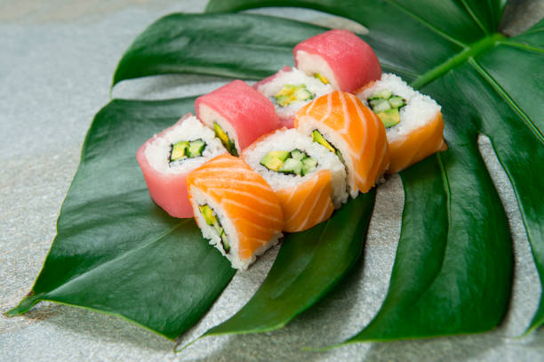 istock sushi roll with salmon, tuna slices served on monstera leaf, gray stone background. 1295874348