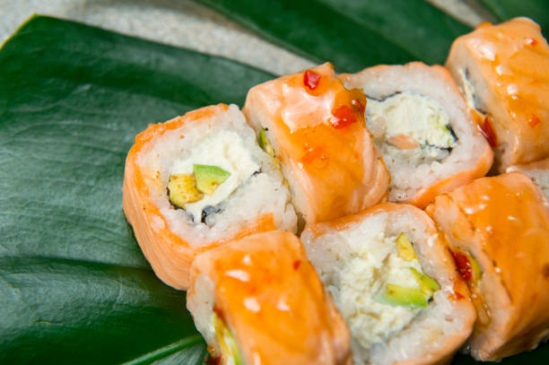 istock Sushi roll with salmon Tataki served on monstera leaf, stone background 1295874972
