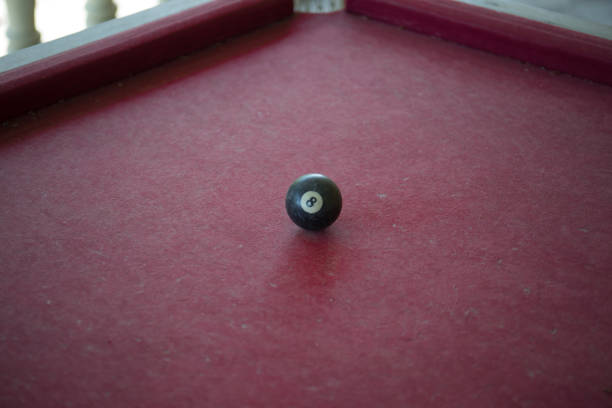 istock Old billiard table outdoor with single black ball. Burgundy colored surface. 1295875228