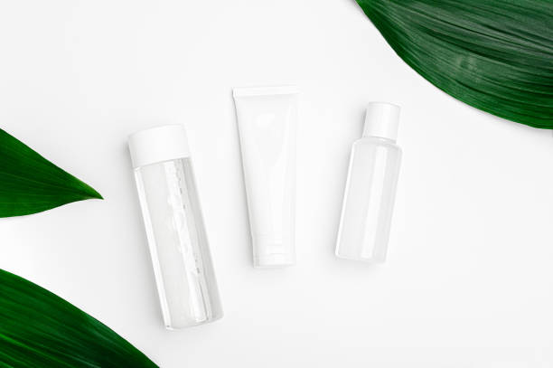 istock Micellar water, cream and lotion in a transparent package on white background with green leaves. Cosmetic natural organic bio products top view. Set of beauty products for face, body and hand skincare 1295877217