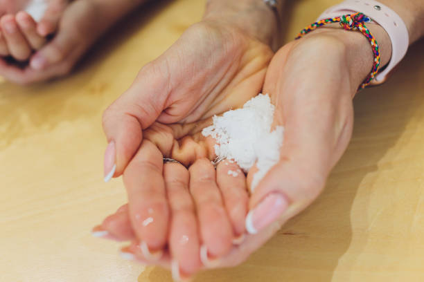 istock Hand holding white polystyrene foam beads ball drop from Styrofoam machine for fragile stuff packaging box on blue modern luxury background for decoration. 1295877463