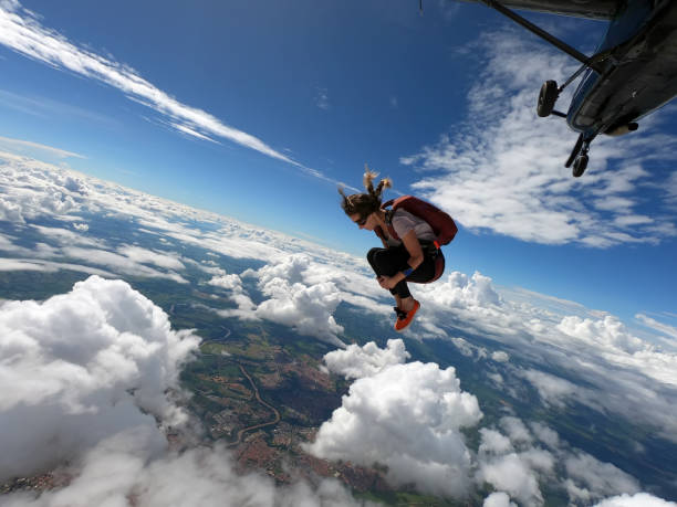 молодая женщина-парашютистка прыгает с самолета - parachuting стоковые фото и изображения