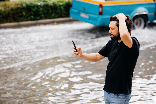 Young men calling for help on her mobile phone after extremely heavy rainfall
