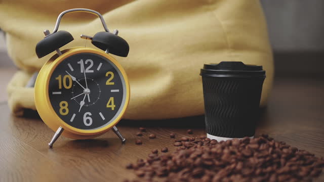 Time lapse.Retro clock with alarm clock,running arrow on the clock,showing 7 o'clock on the hands of the clock.A glass of coffee with coffee beans.Close-up-