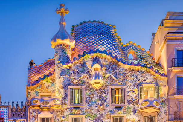 Casa Batllo designed by Antoni Gaudi in downtown Barcelona Spain Visitor stands on the roof of Casa Batllo, house designed by Antoni Gaudi, in downtown Barcelona Spain in the evening. It is a UNESCO World Heritage Site. antoni gaudí stock pictures, royalty-free photos & images