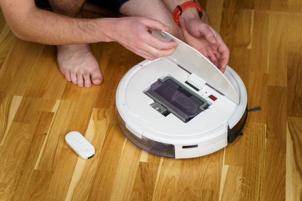 istock Housework and technology concept. Maintenance and service of robot vacuum cleaner. Cleaning, repair, replacement of parts. Man repairing robot cleaner at home. Smart home functions, fully automated 1295893708