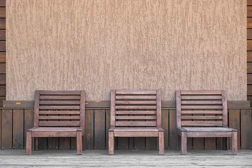 Three empty wooden chairs for relaxing on the hotel's outdoor terrace. Wood trim. Graphic symmetrical lines. Copy space.