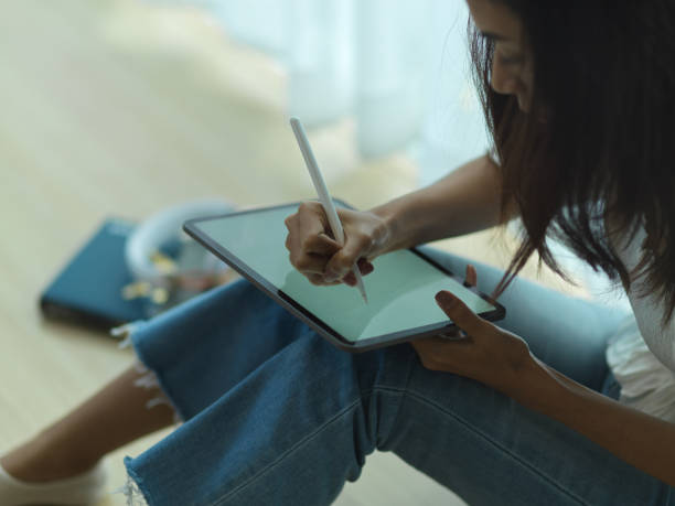 istock Female using digital tablet while relaxed sitting on the floor in living room 1295900247
