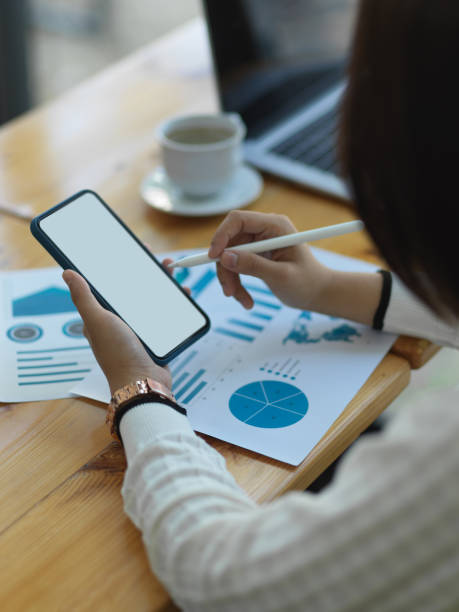 istock Businesswoman using smartphone while analysing business chart in office room 1295901085