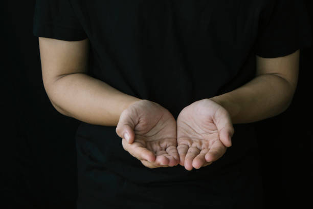 istock needy young man raise his empty hands up to asking for help over black background 1295901860