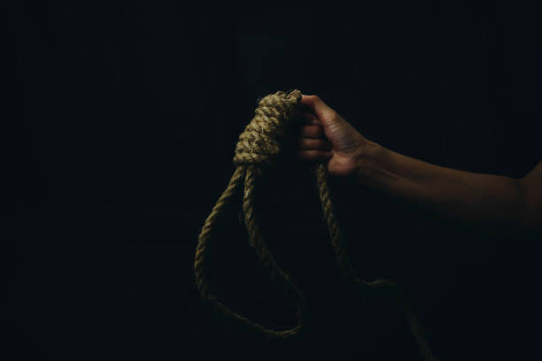 une femme triste retenant la corde avec l’étau du bourreau dans la chambre noire - femme se pendre photos et images de collection