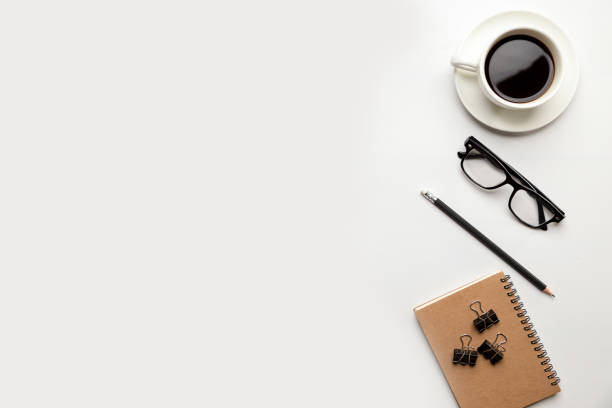 istock Flat lay, top view office table desk. Workspace with blank, office supplies, pencil, green leaf, and coffee cup on white background. 1295906423