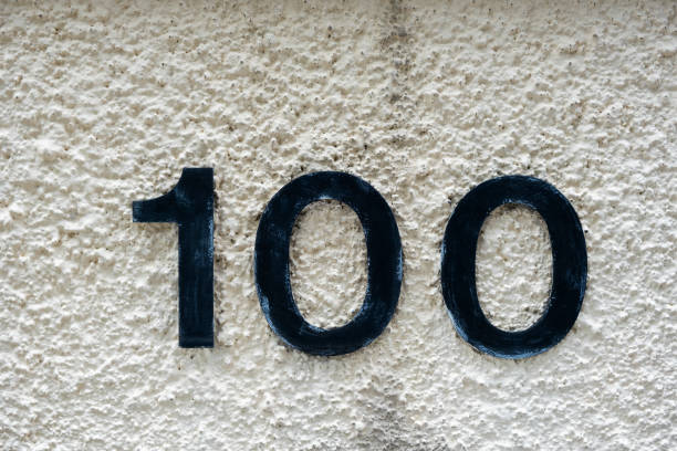 istock House number 100 on a white weathered textured wall 1295911016