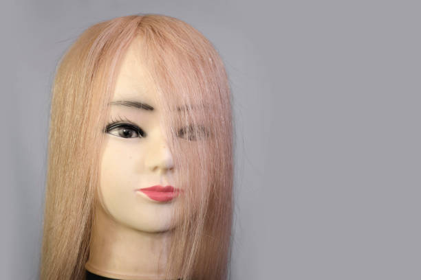 istock Front view of a mannequin head wearing a long blond wig or toupee. 1295911663