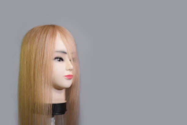 Side view of a mannequin head wearing a long blond wig or toupee.