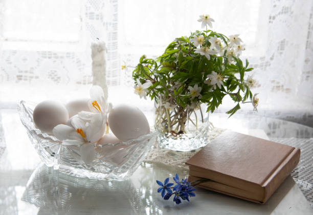 istock Spring flowers in a glass and white eggs in a crystal vase on a white background. 1295912862