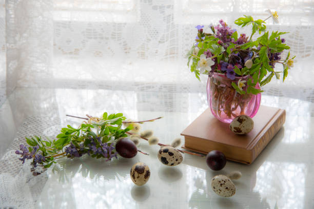 istock Candle, book and Easter eggs by the window - still life on the table as a symbol 1295912882