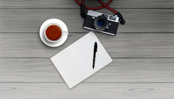 istock Top view blank notebook with film camera and white coffee cup on dark wood background - Flat lay minimal 1295914733