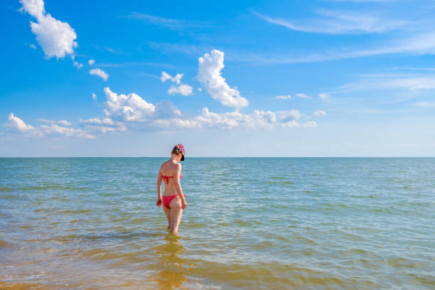 屋外の日光を背景に海の中で一人の魅力的な女性。 - bikini bottom ストックフォトと画像