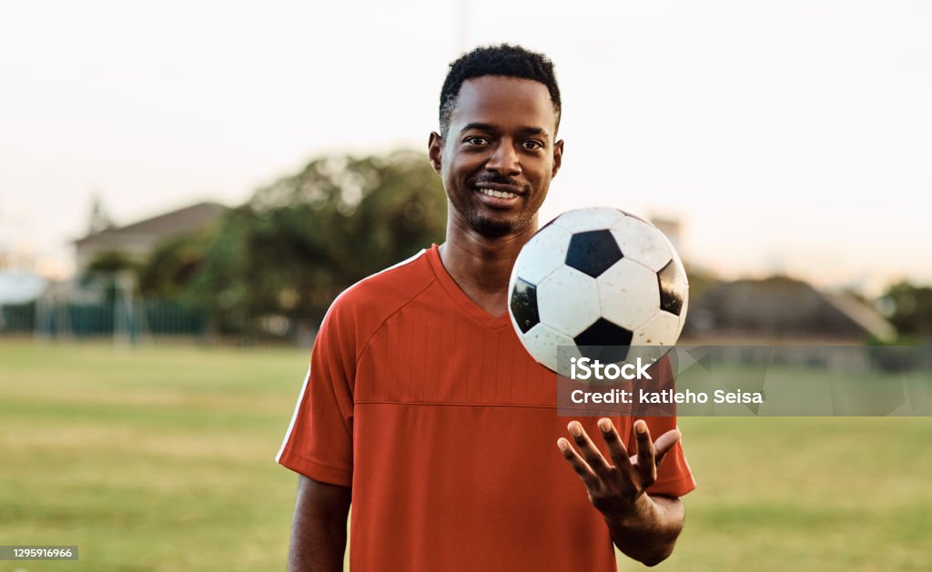 Soccer has taught me a lot Shot of a soccer player holding a ball while out on the field Soccer Player Stock Photo