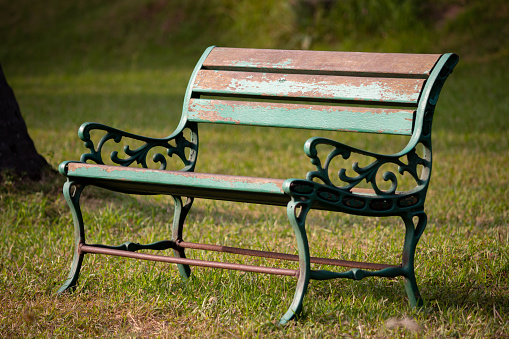 A steel bench in a green grass field. Empty chair in a park. Focus set of chair grill