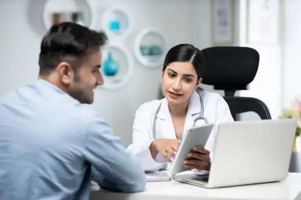 Photo of uses laptop while talking with patient stock photo