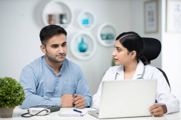 istock uses laptop while talking with patient stock photo 1295918906