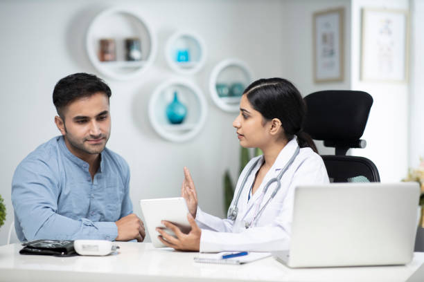 uses laptop while talking with patient stock photo Indian, Doctor, clinic, guidance, doctor stock pictures, royalty-free photos & images