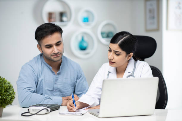istock uses laptop while talking with patient stock photo 1295919839