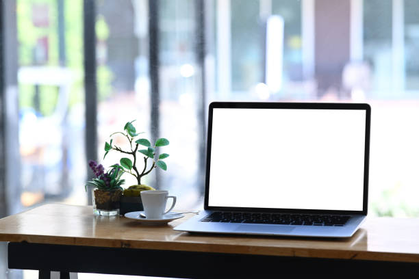 istock Simple workspace with mock up computer laptop, plant, and coffee cup on wooden table. 1295921067