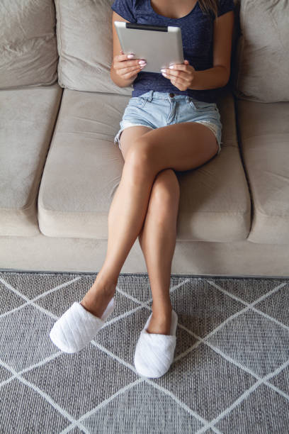 istock Young woman sitting on sofa and using tablet at home 1295922250