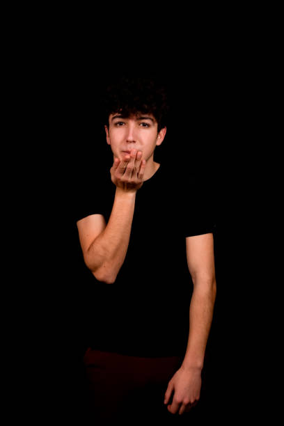 istock Attractive young man with curly hair posing on black background 1295923674