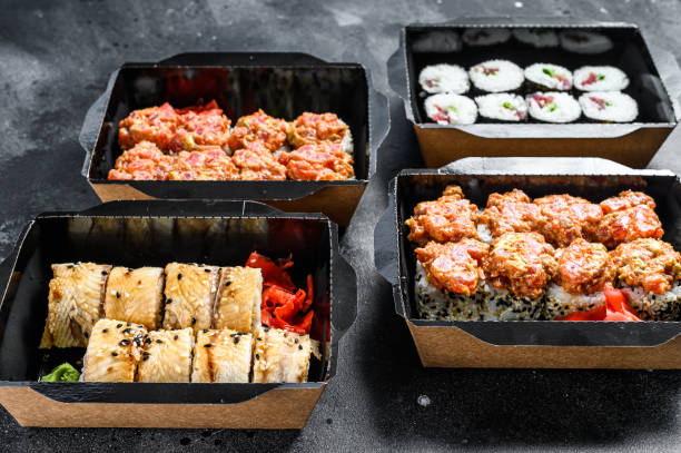 istock The sushi rolls in the delivery package, ordered in sushi take-out restaurant.  Black background. Top view 1295927397