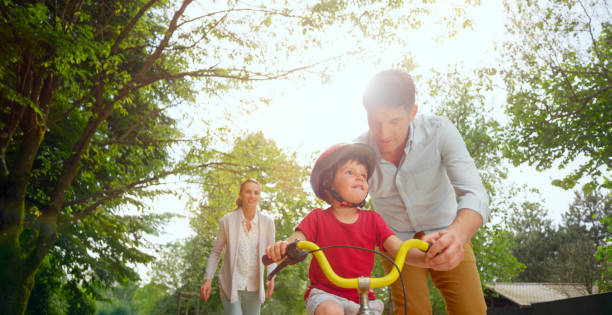istock Father helping son to ride bicycle 1295928744